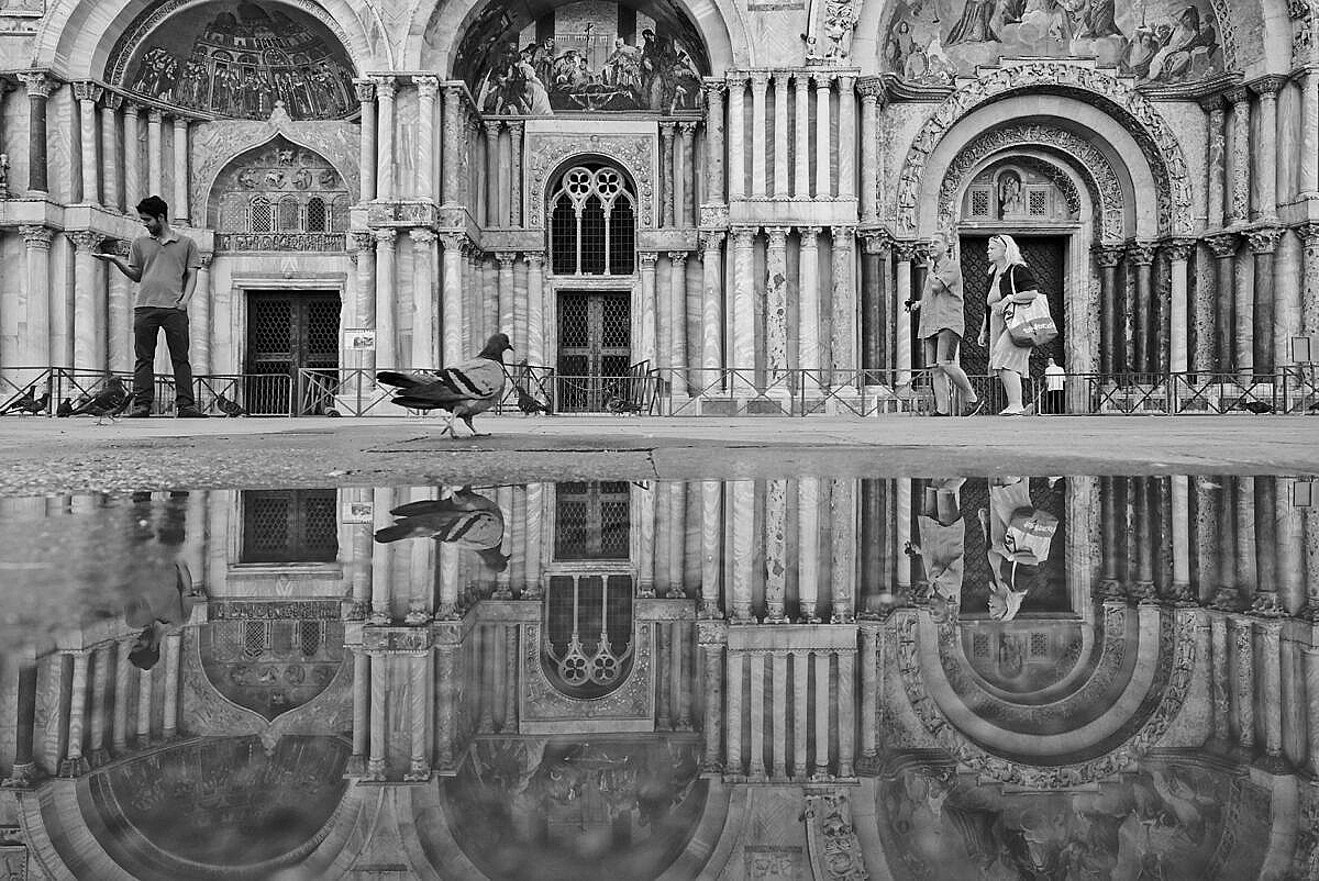 The facade of the Basilica of St. Mark reflected in the tidal water on the square