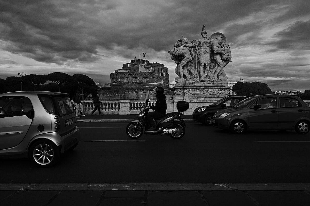 Castel Sant'Angelo in Rome seen from the Ponte Vittorio Emanuele II with lots of traffic and a dramatic sky