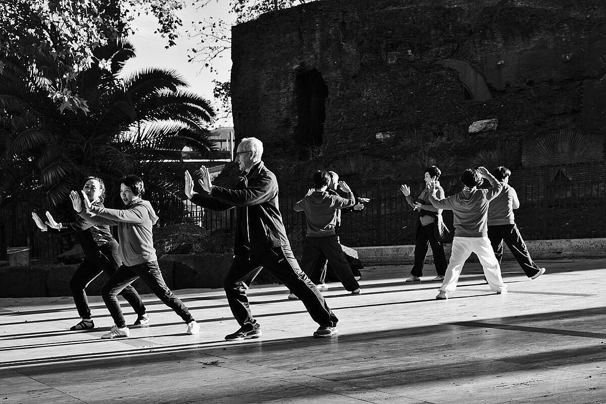 Group of people practising and teaching Tai Chi in a park on the Esquiline Hill in Rome.