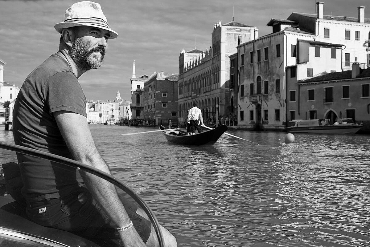 Francesco Penzo on the lookout for the Regata Storica 2018, sitting on the front of his motor boat on the Grand Canal while the local police is rowing past