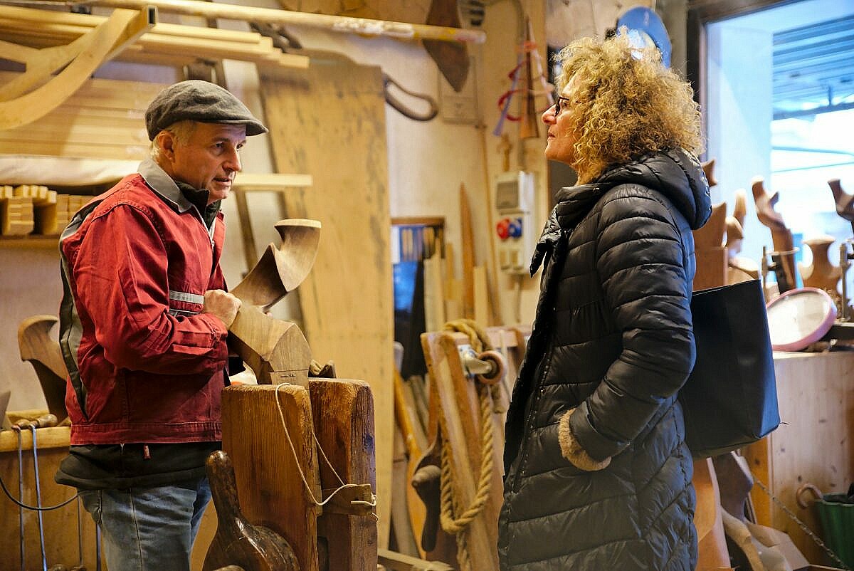 Oarmaker Saverio Pastor chatting with a guest in his workshop, while leaning on a forcola