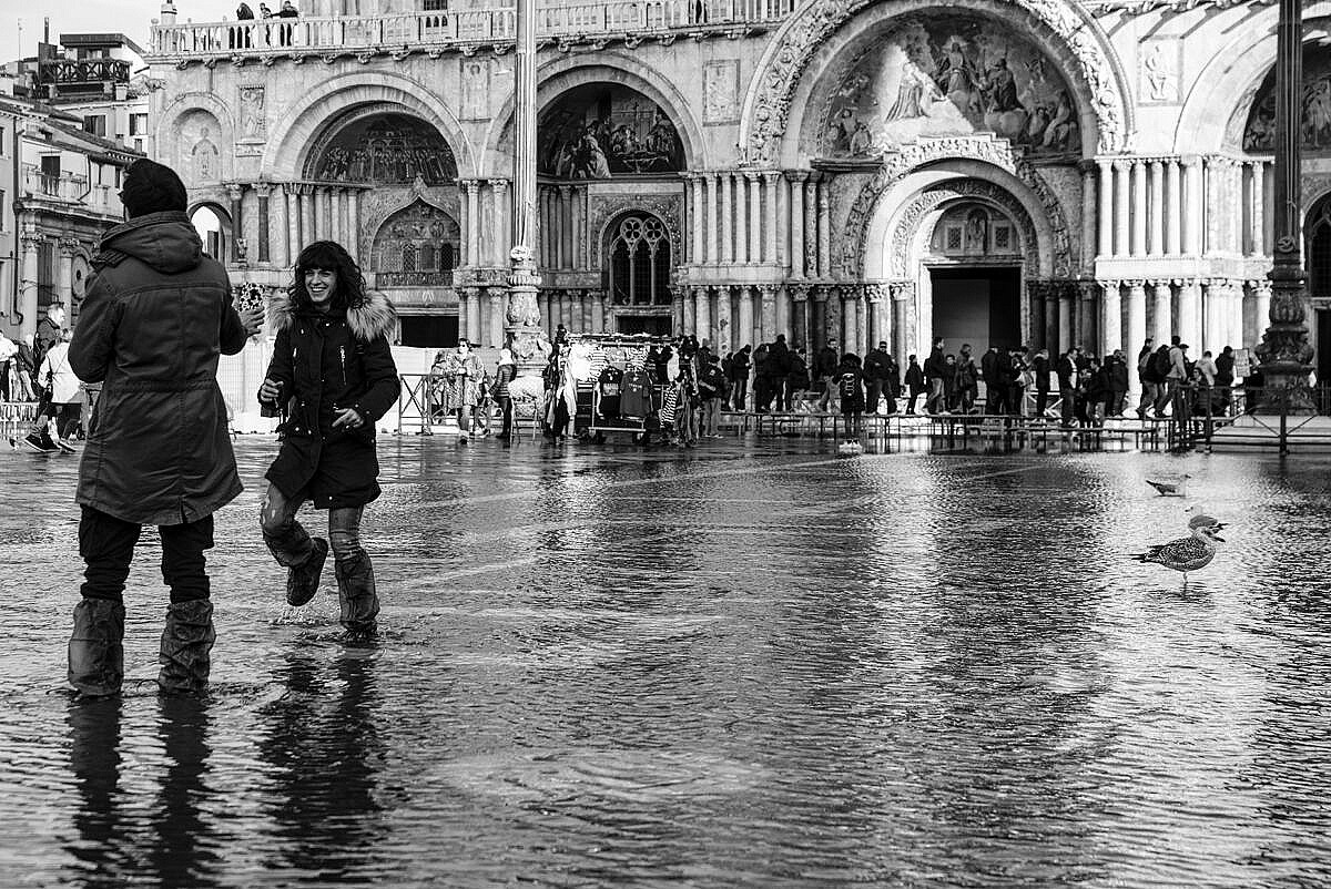 Young couple playing in the high water in St. Mark's square